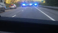 Blurry photo.  RV, SUV on left side of road, multiple police cars with lights flashing.  People seen standing on right side of road.