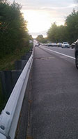 Photo of line of traffic backed up on highway.  One person standing near stopped car.