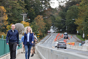 a man and a woman walk across a vehicle bridge
